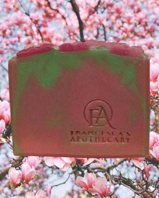 Floral fruity summer scent soap in front of cherry blossoms.