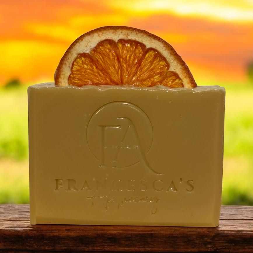 Natural Fruit Bundle soap adorned with an orange slice, showcasing vibrant color against a sunset background.