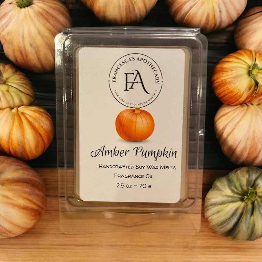 Amber Pumpkin Soy Wax Melt with white pumpkin, coconut, red berries, cinnamon, clove, amber, cedar, sandalwood, and vanilla notes displayed among pumpkins.