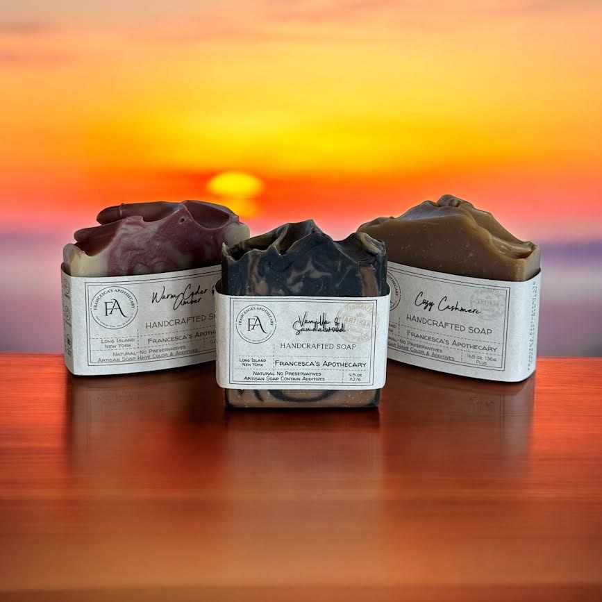 Earthy Woody Amber soap bundle displayed on a wooden surface with a sunset background.
