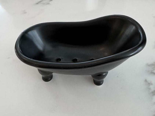 Black ceramic tub soap dish with drainage holes.