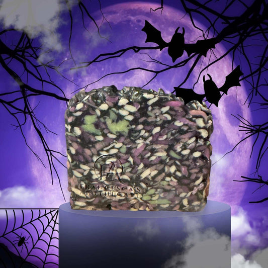 Twilight Moon Artisan Soap with black, purple, and green swirls on a pedestal against a spooky purple moon background with bats and spider webs.