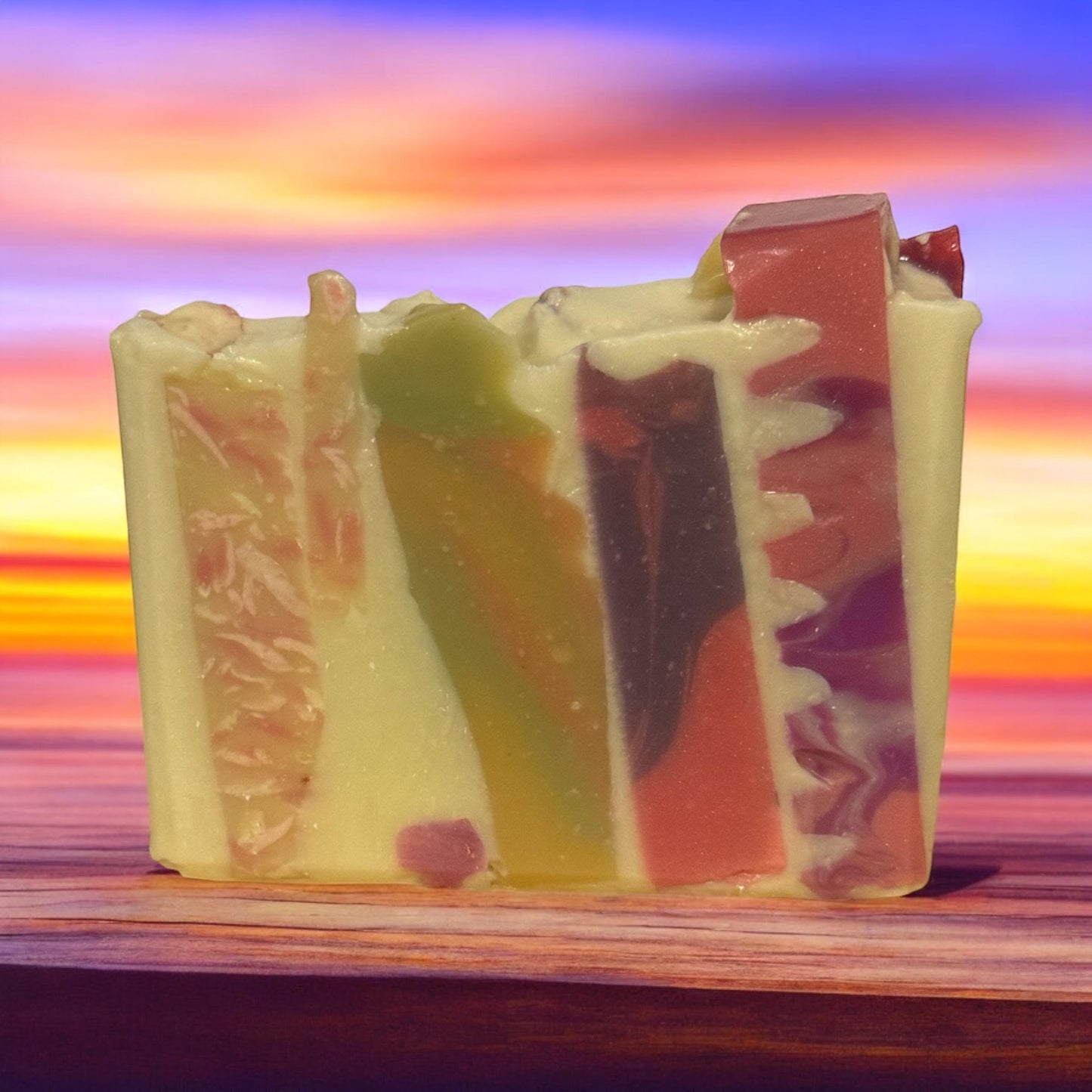 MOSAIC - Sweet Mosaic Soap with colorful layers on a wooden surface against a sunset background.