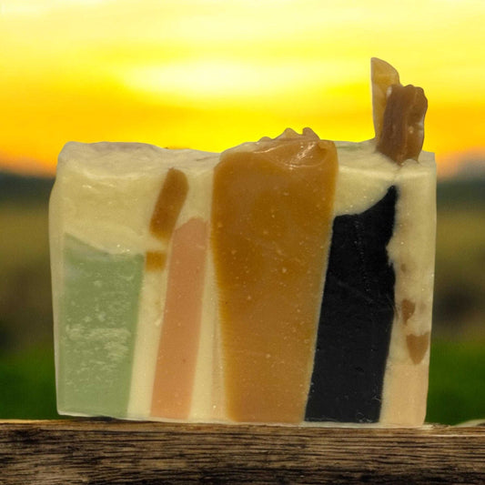 Mosaic style soap bundle with colorful layers against a sunset backdrop.