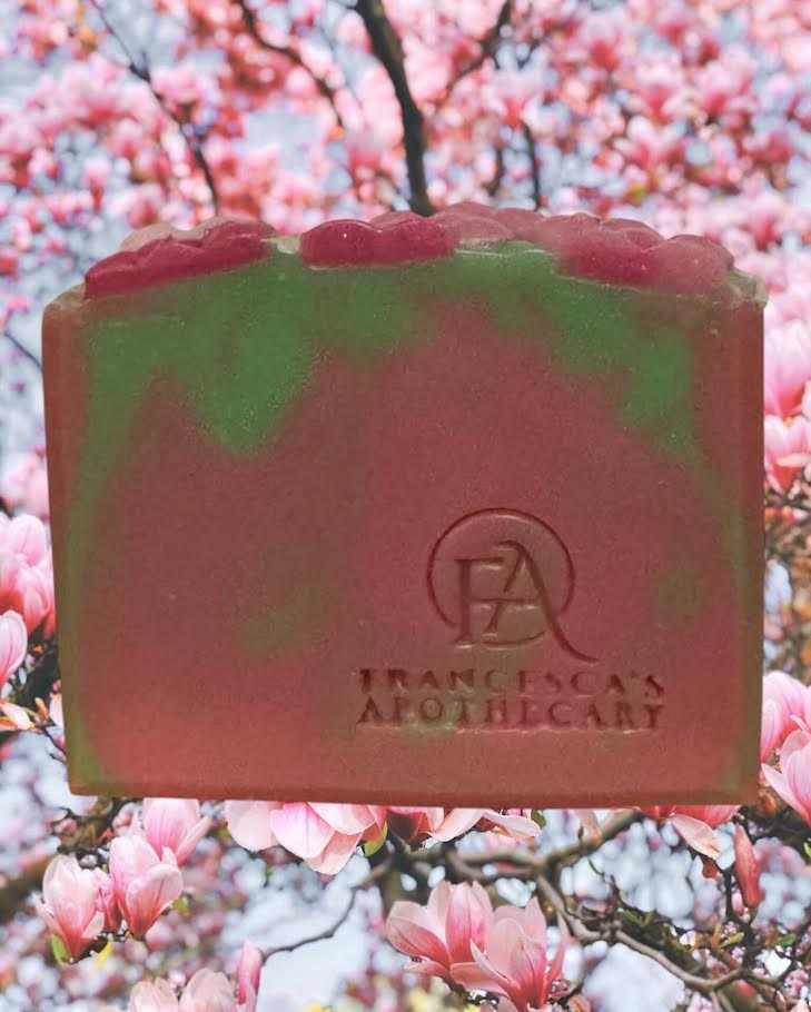 Floral fruity summer scent soap with pink and green swirl design, embossed with Francesca's Apothecary logo, set against a cherry blossom background.
